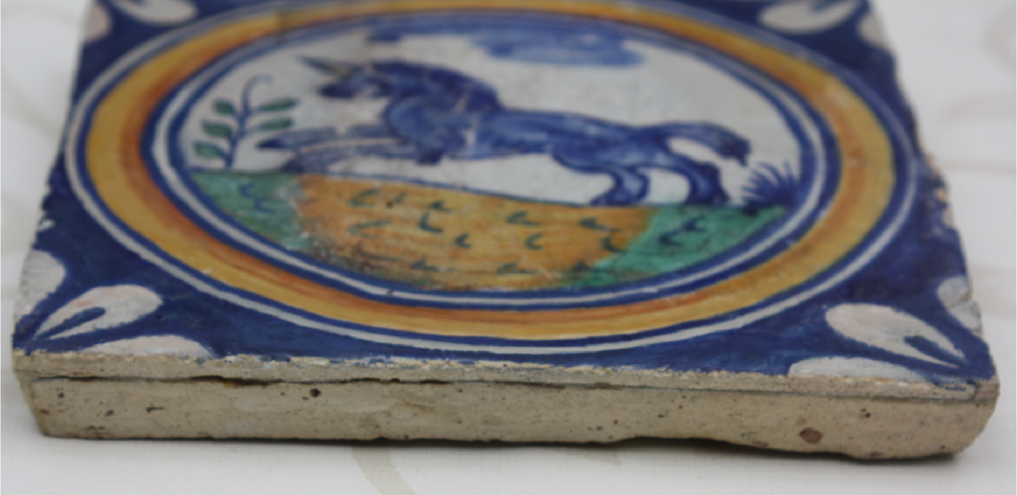A rare 1600 hand-painted polychrome Delft stonework medallion tile, showing a running unicorn