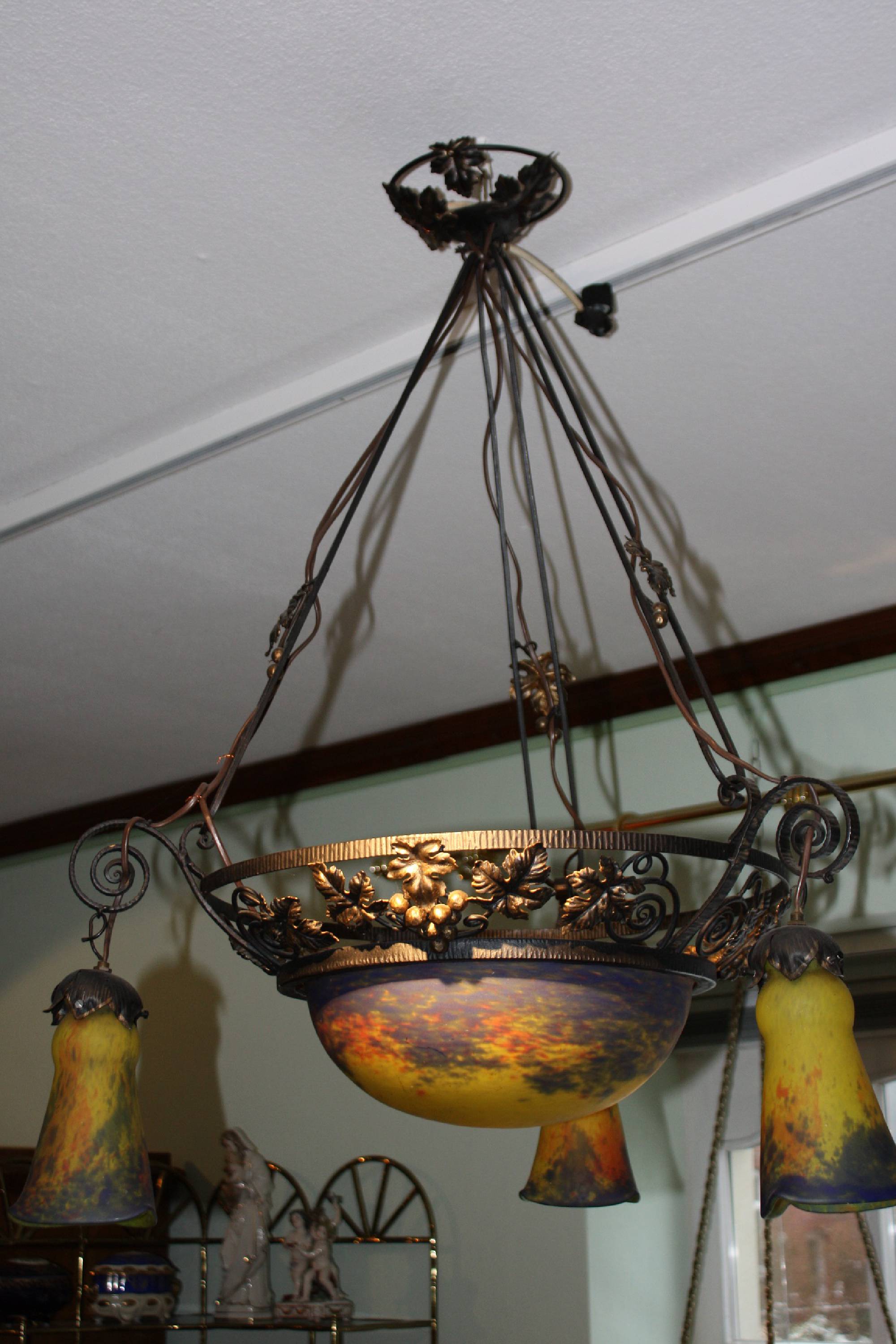 A french 1920's wrought-iron Art Nouveau ceiling lamp ornamented with vines, with three mattted polychrome lampshades and cupola