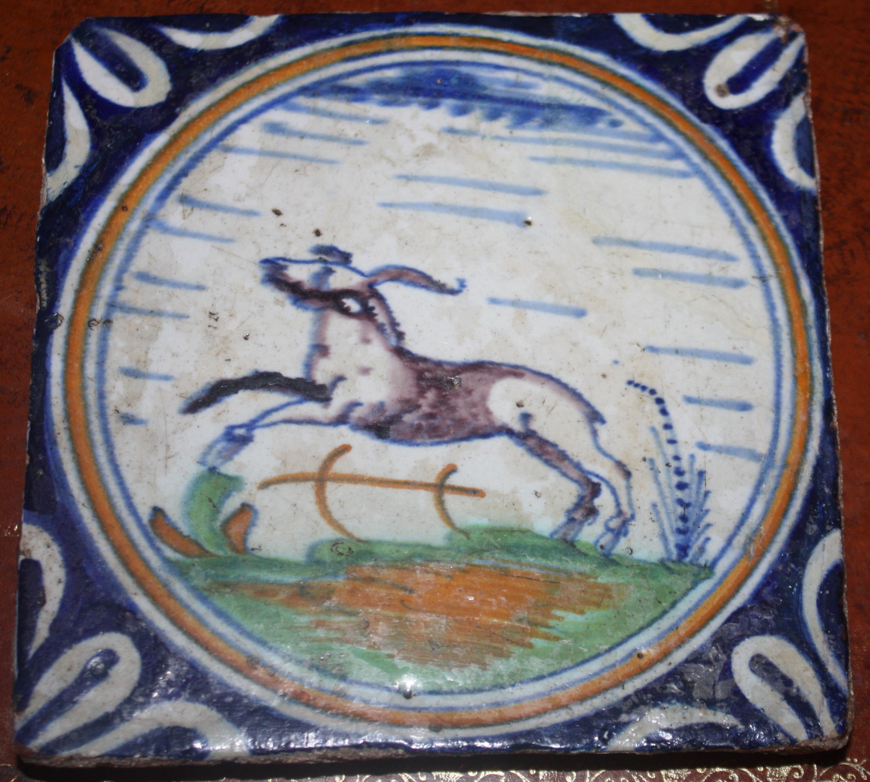 A 17th century Delft polychrome stoneware tile displaying a jumping roebuck