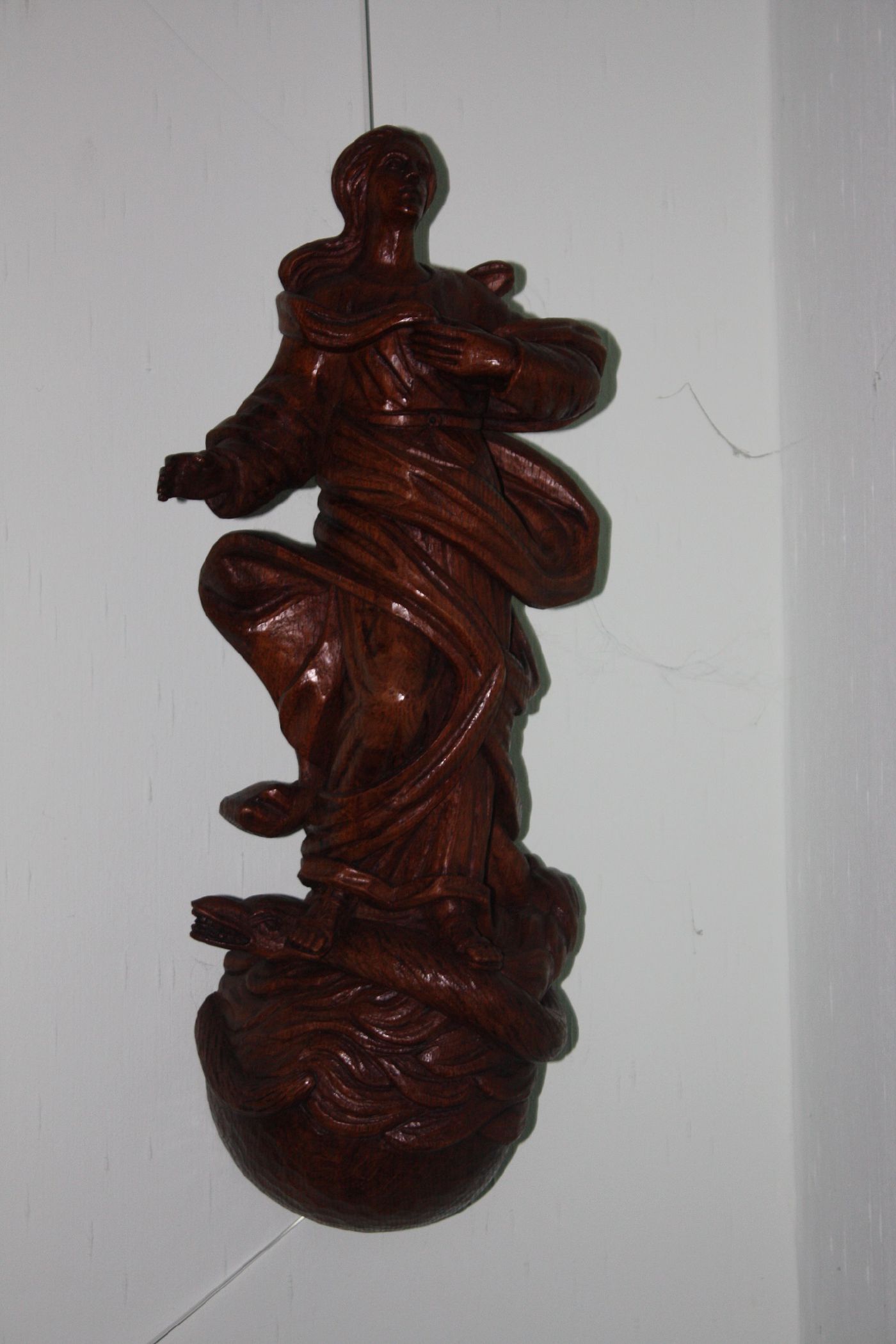 A large wooden 20th century handcarved Virgin Mary treading on a snake figure wall statue