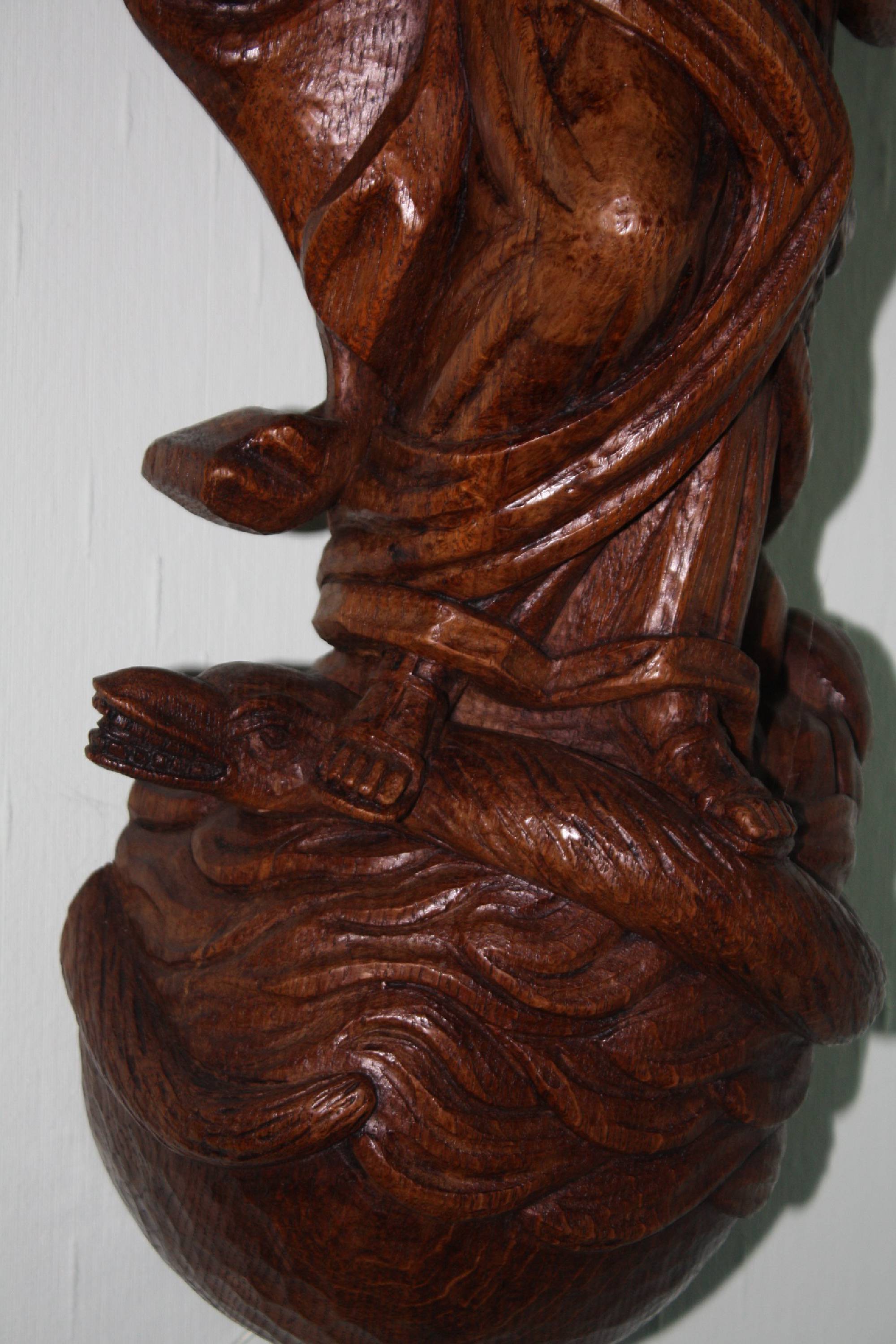 A large wooden 20th century handcarved Virgin Mary treading on a snake figure wall statue