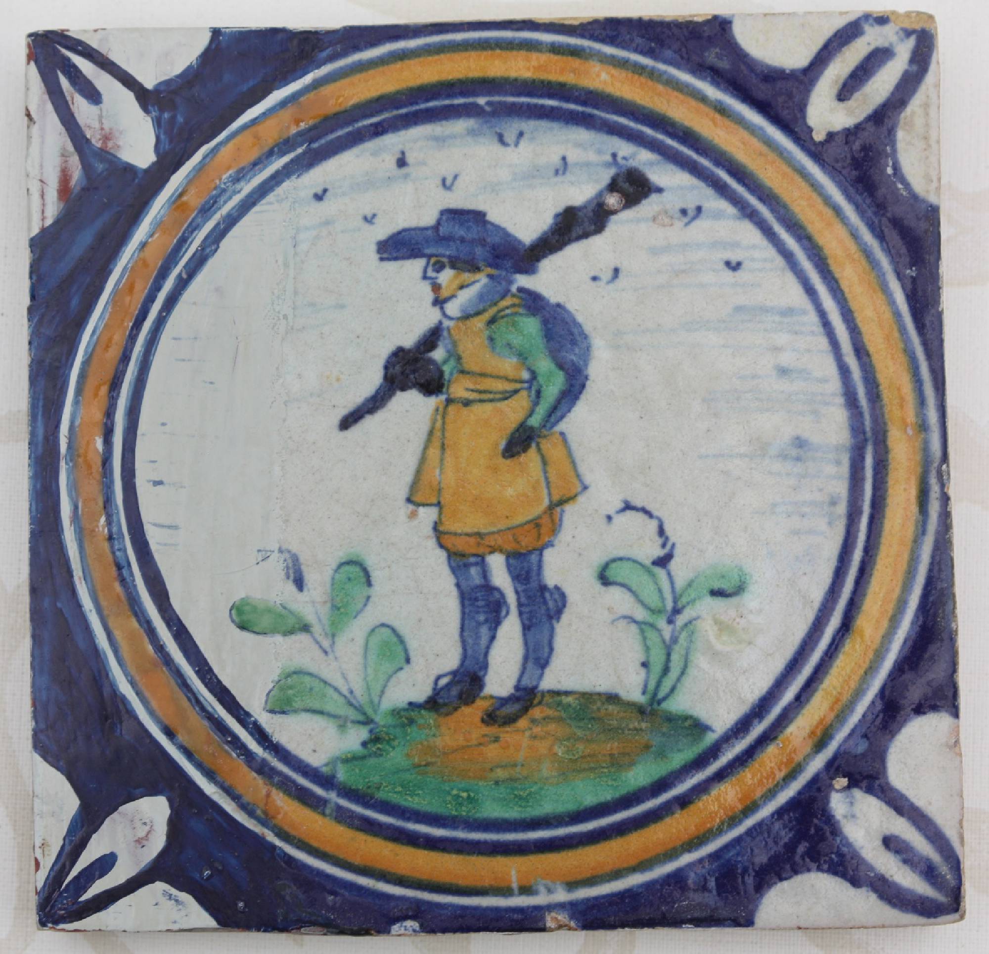 First half 17th century hand-painted antique polychrome Dutch stoneware medallion tile, showing a musketeer