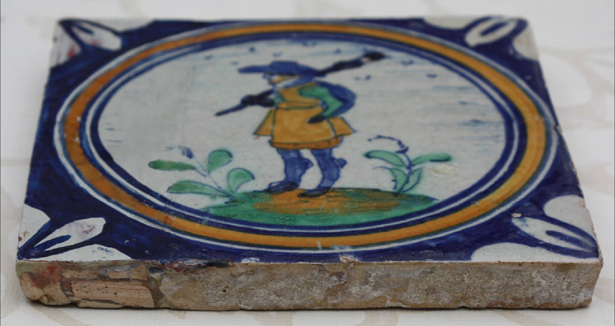 First half 17th century hand-painted antique polychrome Dutch stoneware medallion tile, showing a musketeer
