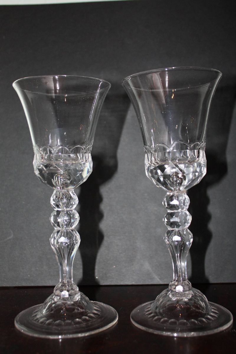 A pair of decorative tall antique 18th century ornate wine glasses on folded foot