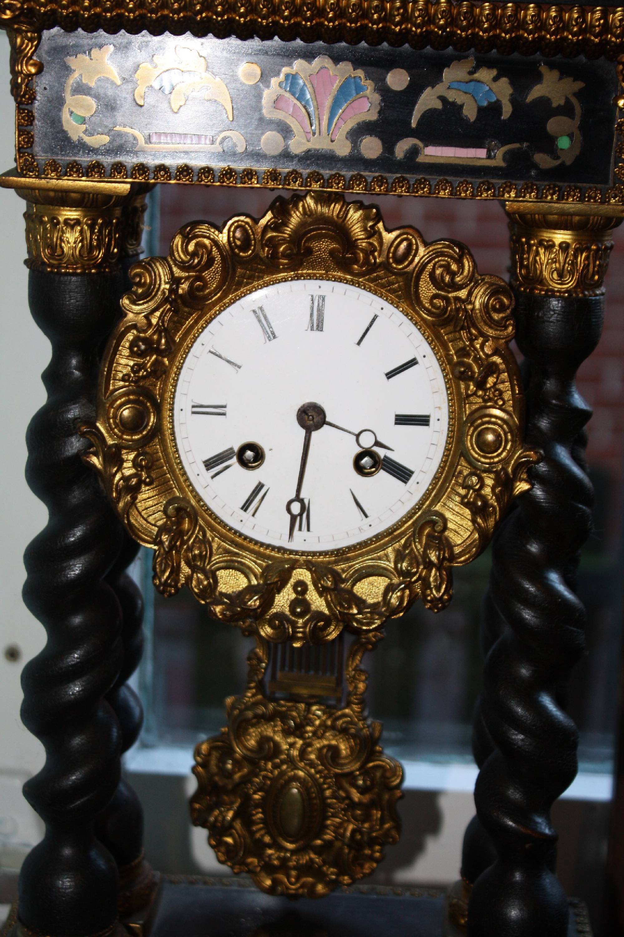 A French ornate antique 19th century mantel clock with four ebonized tortuous pillars and inlays