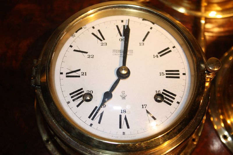 A 20th century German set of a brass ship clock, a brass steerwheel case barometer and a brass hygrometer with thermometer, each one made by 'Wempe', Hamburg, Germany